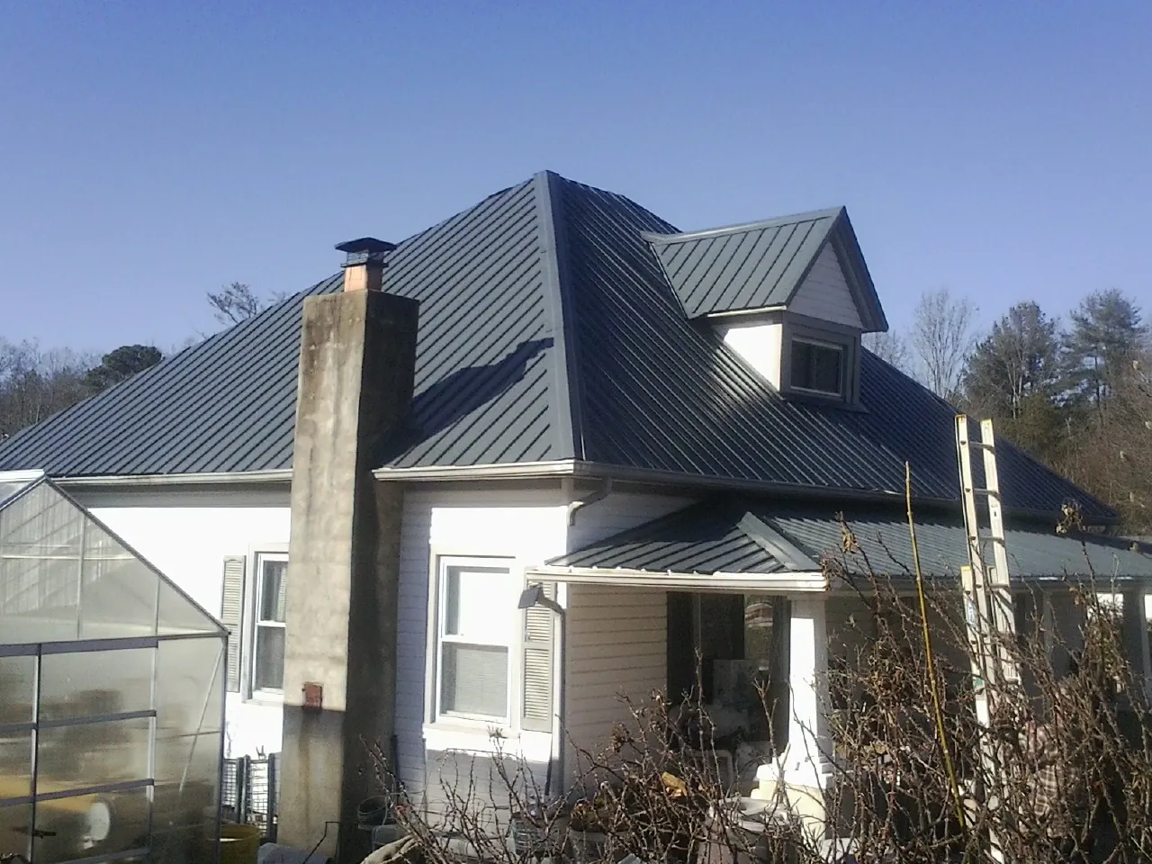 Dark blue standing seam metal roof on a white farmhouse with dormer — Slate & Tile Roof Repair by Roofing Brothers in Dawsonville