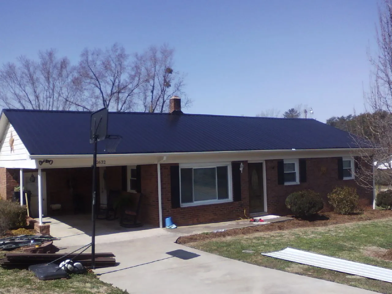 Finished dark blue metal roof on a brick ranch with a carport in Dawsonville
