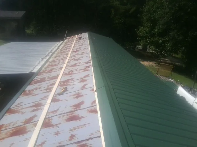 Old rusted panels beside newly installed green metal roofing — Wind Damage Roof Repair by Roofing Brothers in Dawsonville