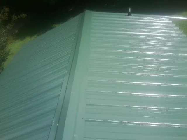 New green metal panels meeting at the ridge of a roof — Flat Roof Repair work by our crew in Dawsonville