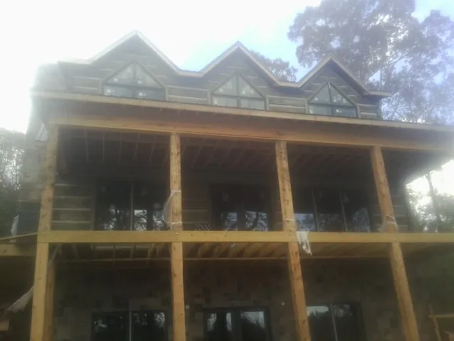 Dormers and porch framing on a large log home under construction — Roof Coating work by our crew in Dawsonville