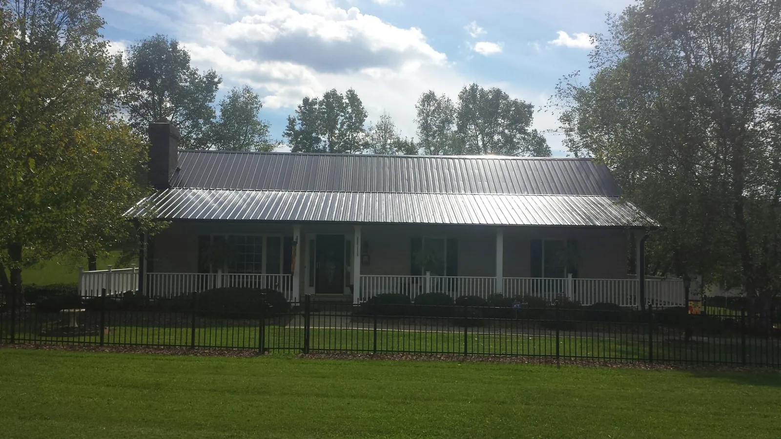 Gray metal roof on a brick ranch with a full width front porch — Gutter Guard Installation work by our crew in Dawsonville