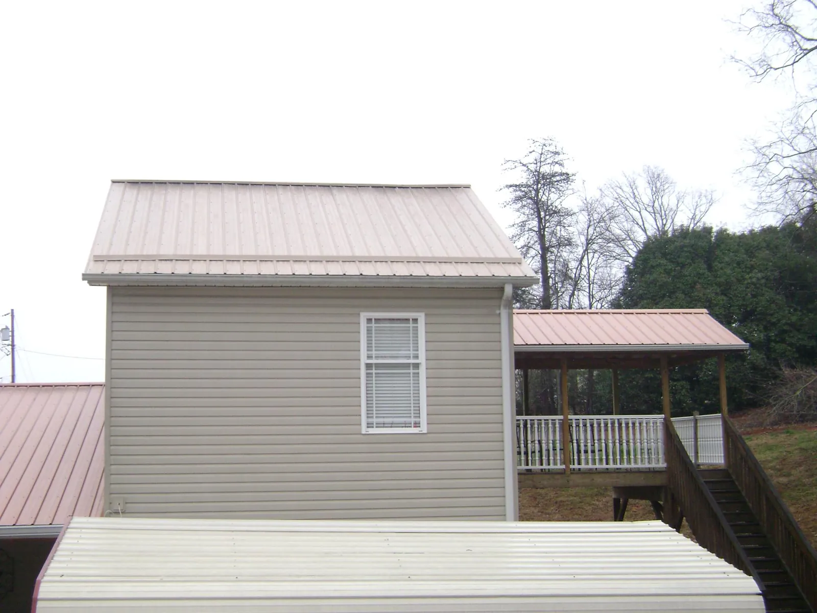 Tan metal roofs on a two story addition and attached porch, from a Roof Replacement job in Dawsonville