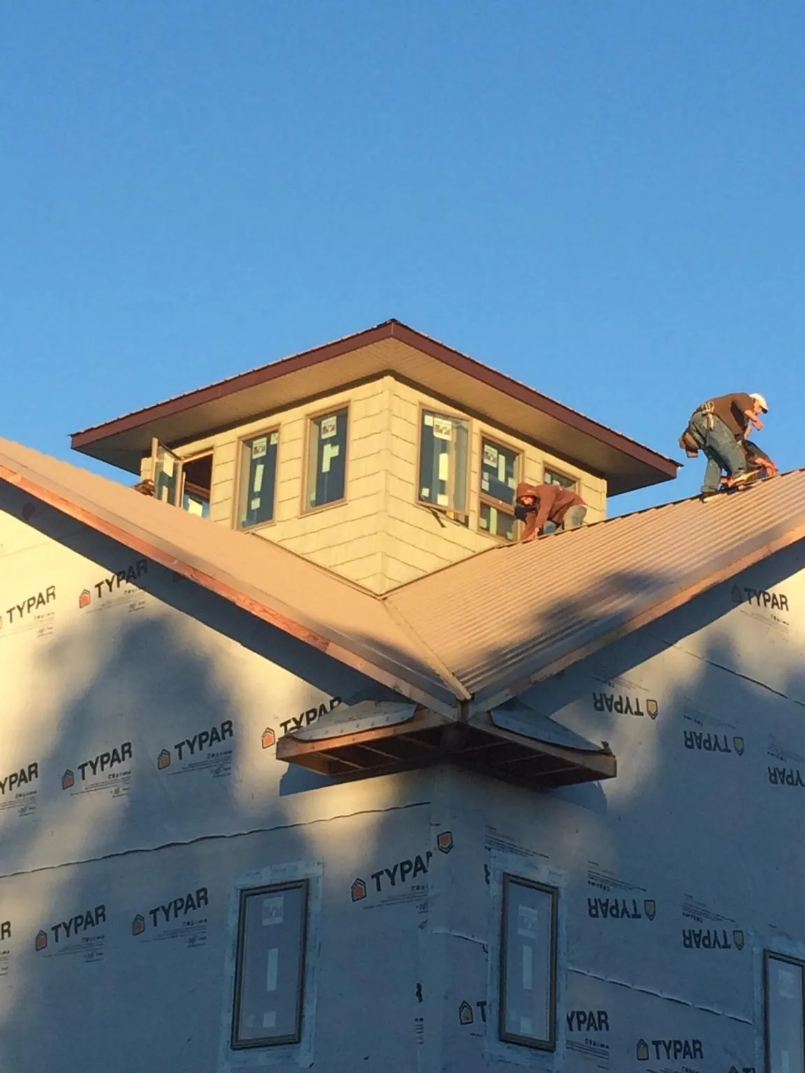 Roofers working around a rooftop cupola on a new metal roof at sunset — Roof Waterproofing in Dawsonville by Roofing Brothers